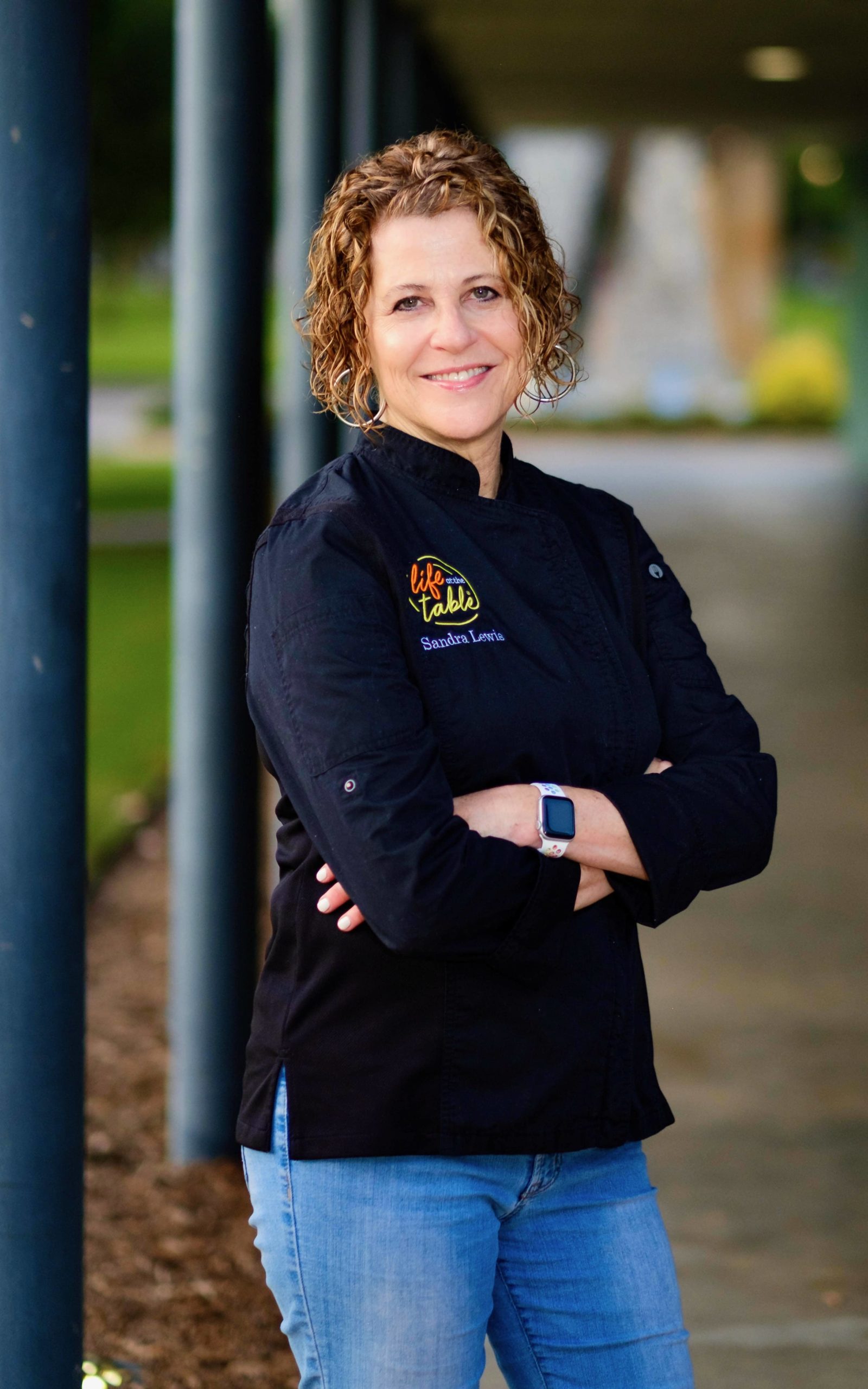 Chef Sandra Lewis of Life At The Table in a chef jacket.